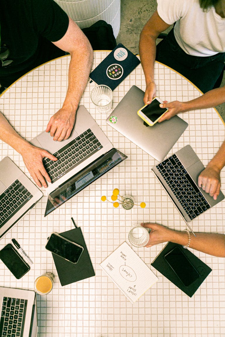 Is This Your Path to High-Ticket Commissions 2 Top view of a team collaborating with laptops, phones, and notes in a modern office.